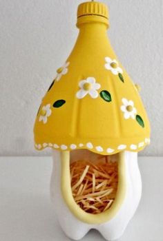 a yellow and white birdhouse with flowers on it's roof is sitting on a table