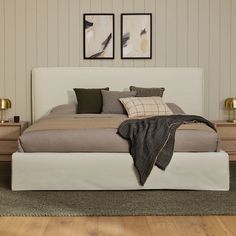 a large bed sitting on top of a wooden floor next to two pictures above it