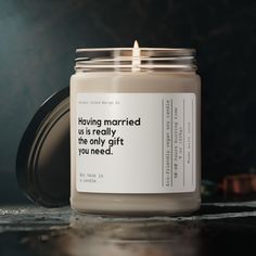 a candle with a quote on it sitting on top of a table next to a cup