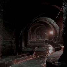 a dark tunnel with water running through it and light coming from the end at the end