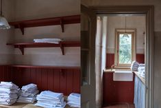 a bathroom with red walls and shelves filled with folded towels in front of a window