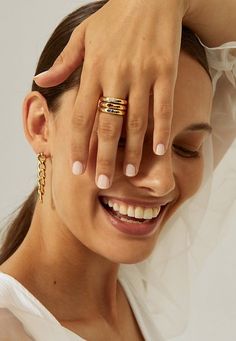 a woman wearing two gold rings on her left hand and holding the top of her head