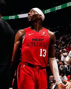 a man in red uniform standing on the court with his headband up and people watching