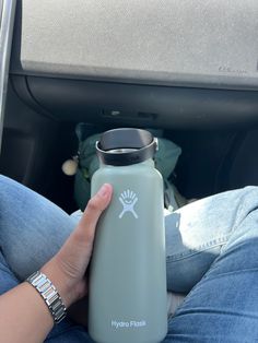 a person holding a water bottle in their lap