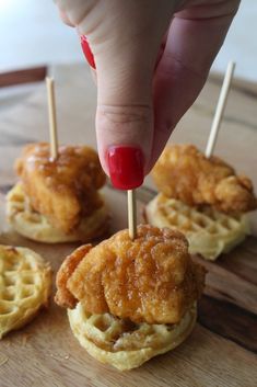 a person is picking up some food from the waffles on skewers