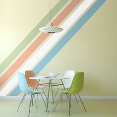 a dining table with four chairs in front of a wall painted with multicolored stripes