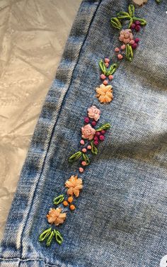 a pair of jeans with embroidered flowers on them