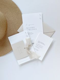 the wedding stationery is laid out on top of each other with a straw hat