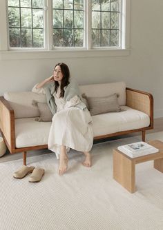 a woman sitting on a couch in front of a window with her feet propped up