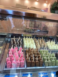 a display case filled with lots of different types of cakes and cupcakes on skewers