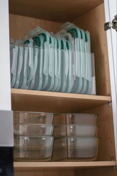 the shelves are filled with dishes and plastic containers