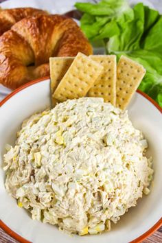 a bowl of chicken salad with crackers on the side