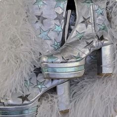 a pair of silver high heeled shoes with stars on the side and fur around them