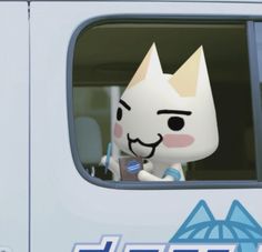 a white cat sitting in the drivers seat of a bus with a toothbrush in it's mouth