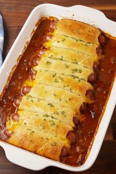 a casserole dish with beans, cheese and bread in it on a wooden table