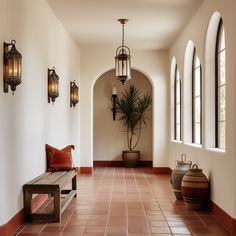 a long hallway with two benches and large windows on either side of the room, along with potted plants