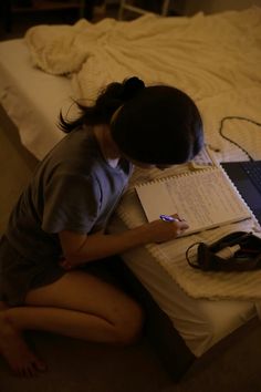 a woman sitting on the floor writing in front of a laptop computer