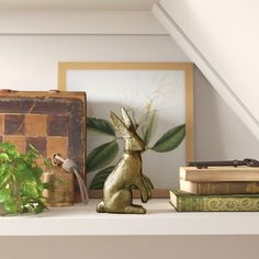 a rabbit figurine sitting on top of a shelf next to books and plants