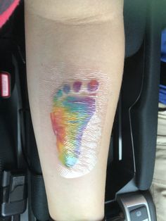 a person's foot with an imprint on the side of their leg that is covered in multicolored paint