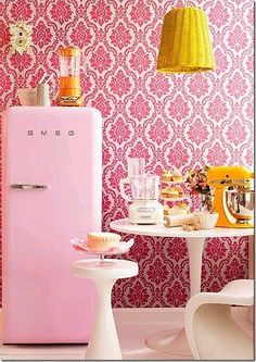 a pink refrigerator sitting next to a white table