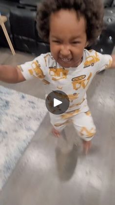 a toddler is smiling and dancing on the floor