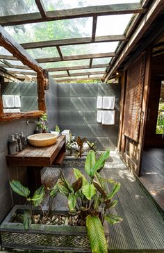 a bathroom with a sink, mirror and plants in the middle of it on a wooden floor