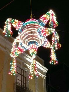 a large christmas light decoration hanging from the side of a building in front of a clock tower