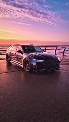 an audi car parked on the beach at sunset with clouds in the sky behind it