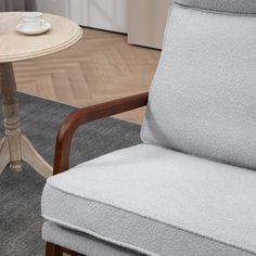 a gray chair sitting next to a table with a white cup on top of it