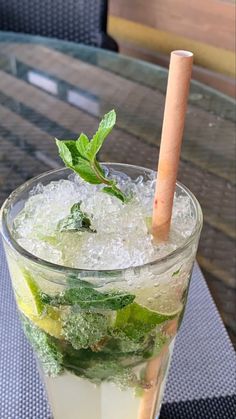 a glass filled with ice and mint sitting on top of a table next to a wooden stick