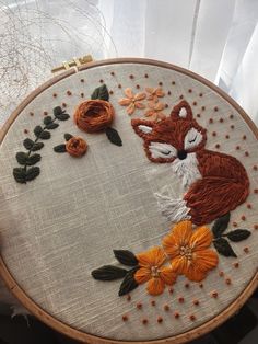 a close up of a embroidery on a table with flowers and a fox face in the middle