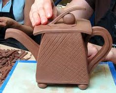 a person is making a teapot out of clay