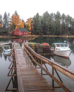 a boat is docked at a dock with other boats and houses in the background on a lake