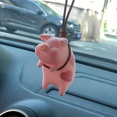 a pink pig hanging from the dashboard of a car