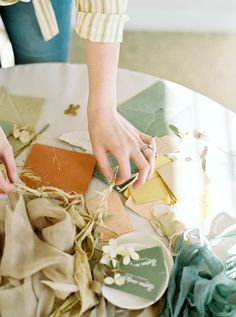 a person cutting paper on top of a table with scissors and other crafting supplies