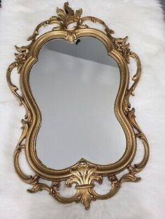 an ornate gold framed mirror on white fur