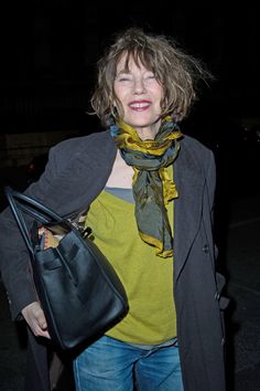 a woman carrying a black purse and wearing a yellow shirt is smiling at the camera