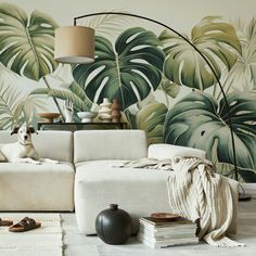 a dog sitting on a white couch in front of a wallpapered with tropical leaves