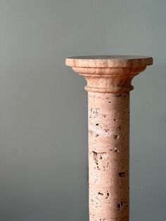 an old stone pillar stands in front of a gray wall