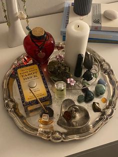 a silver tray with candles, books and other items sitting on top of the table