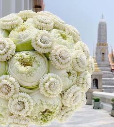 a bouquet of white flowers sitting on top of a glass vase in front of a building