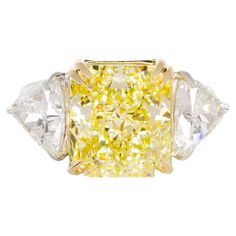 a fancy yellow diamond ring with three pear shaped diamonds on the sides and four prongs