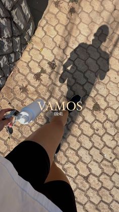 the shadow of a person holding an object in their hand, on a cobblestone walkway