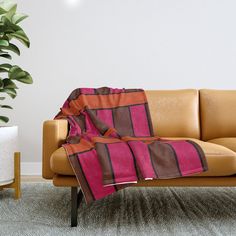 a couch with a blanket on it next to a potted plant