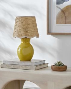 a yellow table lamp sitting on top of a book next to a small succulent plant