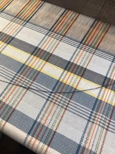 a plaid tablecloth is sitting on top of a wooden table with an orange and blue stripe