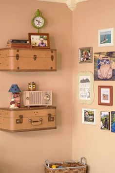 two suitcases are stacked on the wall above a bed with a basket underneath them