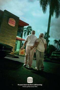 an older couple walking down the street in front of a burger king