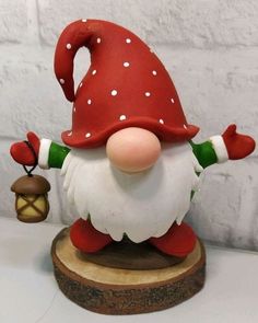 a red and white gnome figurine holding a lantern on top of a wooden base