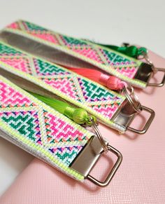 two pink, green and yellow lanyards with metal clips on top of them